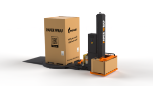 Automated packaging line with a large cardboard box labeled PAPER WRAP on a pallet beside a tall black wrapping machine.